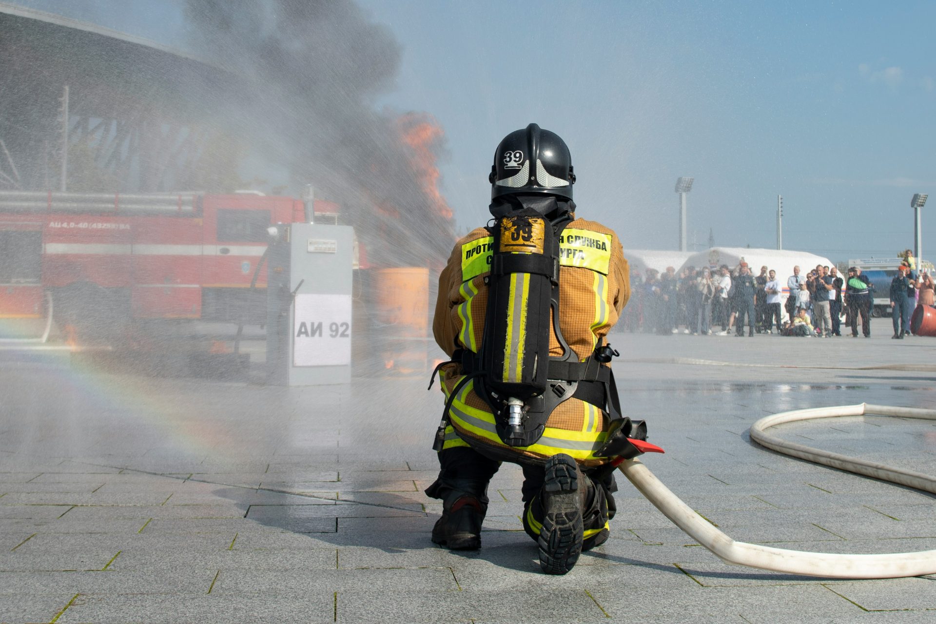 Ein Feuerwehrmann in voller Ausrüstung sprüht Wasser auf ein Feuer.